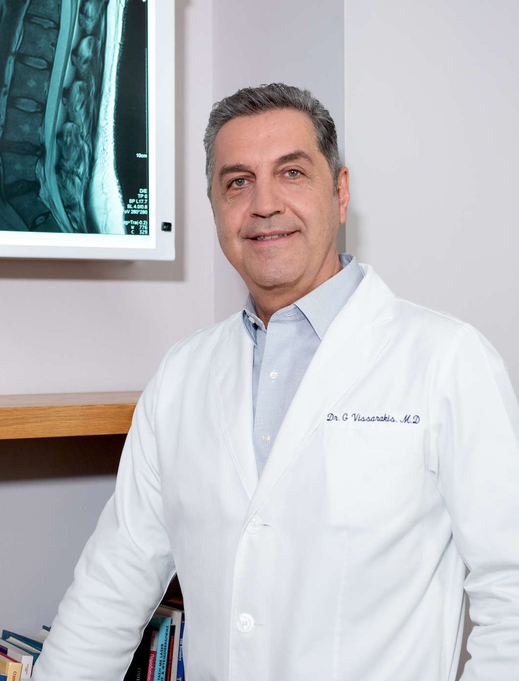 Ο Γεώργιος Βησσαράκης στο ιατρείο του με φόντο μία ακτινογραφία